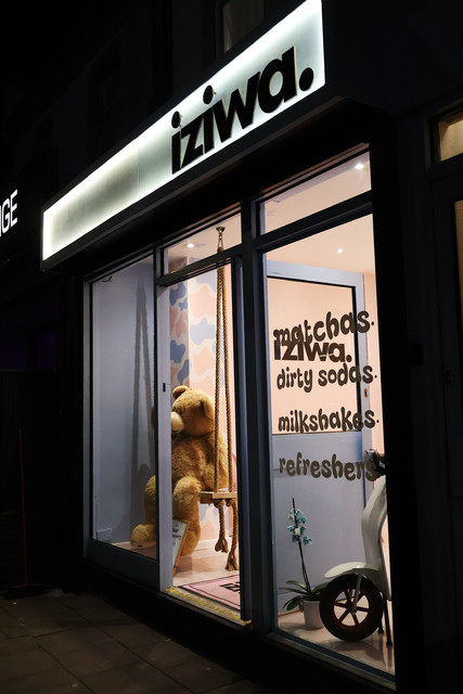 The Iziwa shopfront on Ley Street, Ilford at night, lit sign above windows reading matchas, dirty sodas, milkshakes and refreshers