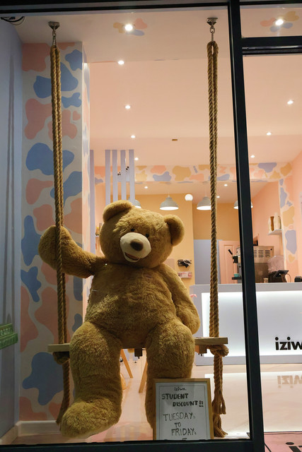 The Iziwa window display, a giant teddy bear sitting on a rope swing